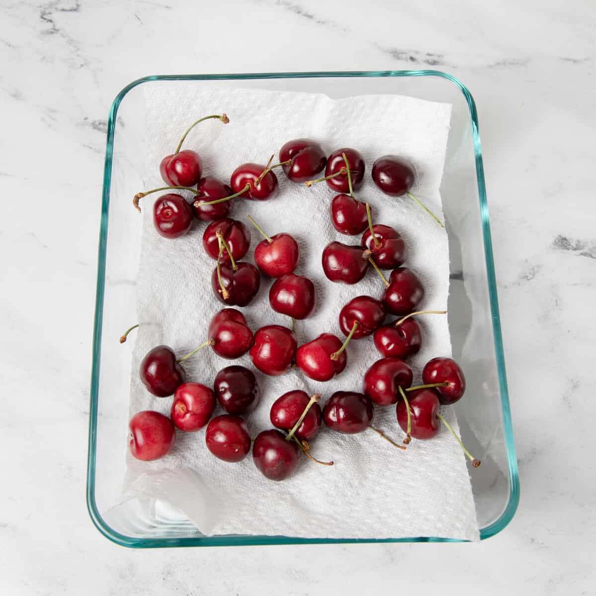 Cherries in a storage container with a towel.