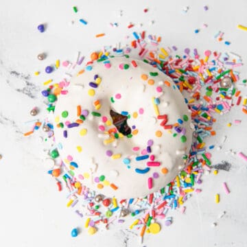 A donut on a counter with sprinkles.