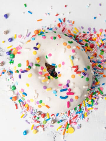 A donut on a counter with sprinkles.