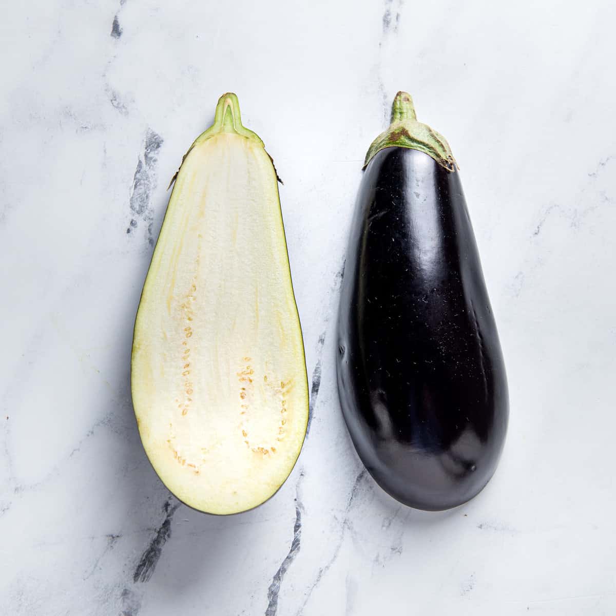 Eggplant sliced in half on a counter.