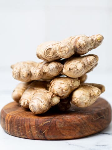 Ginger stacked on a wooden board on a counter.