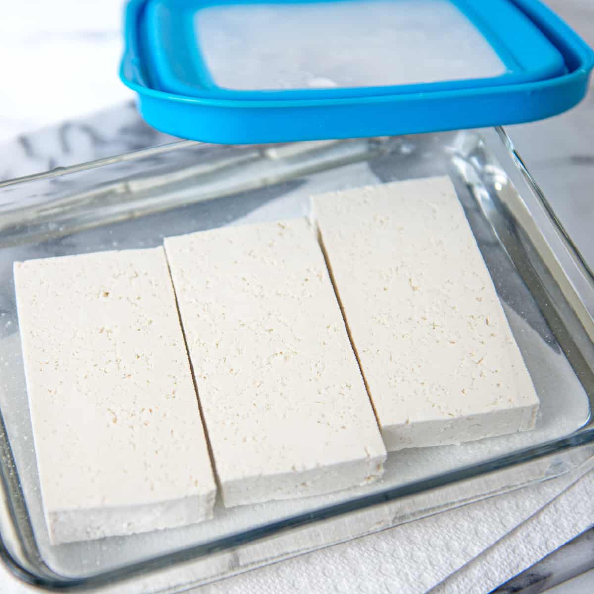 Leftover tofu uncooked in a glass container.