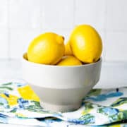 Lemons in a white bowl on a colored kitchen cloth.