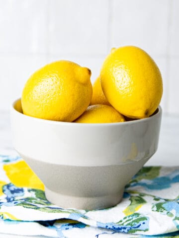 Lemons in a white bowl on a colored kitchen cloth.
