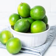Limes in white bowl with a napkin.
