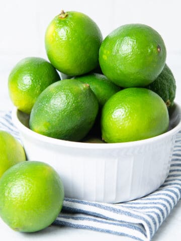 Limes in white bowl with a napkin.