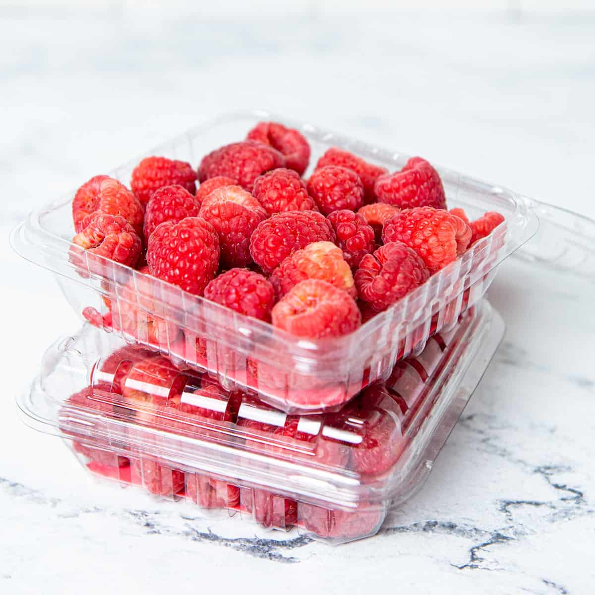 Raspberries in containers on a counter.