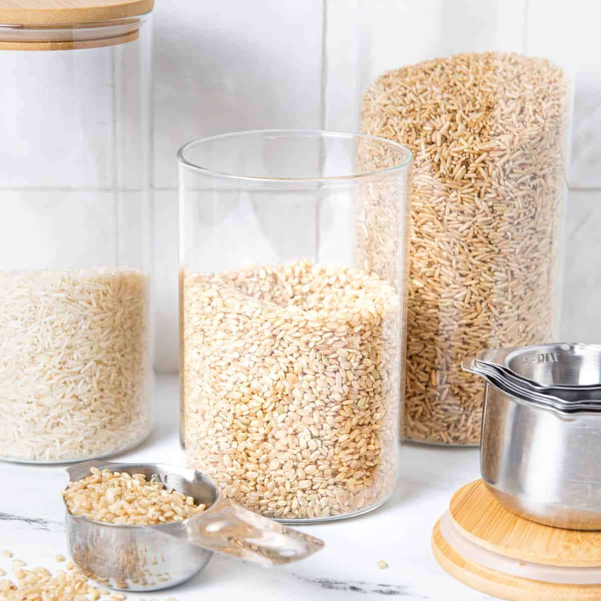 Rice in jars on counter with scoops.