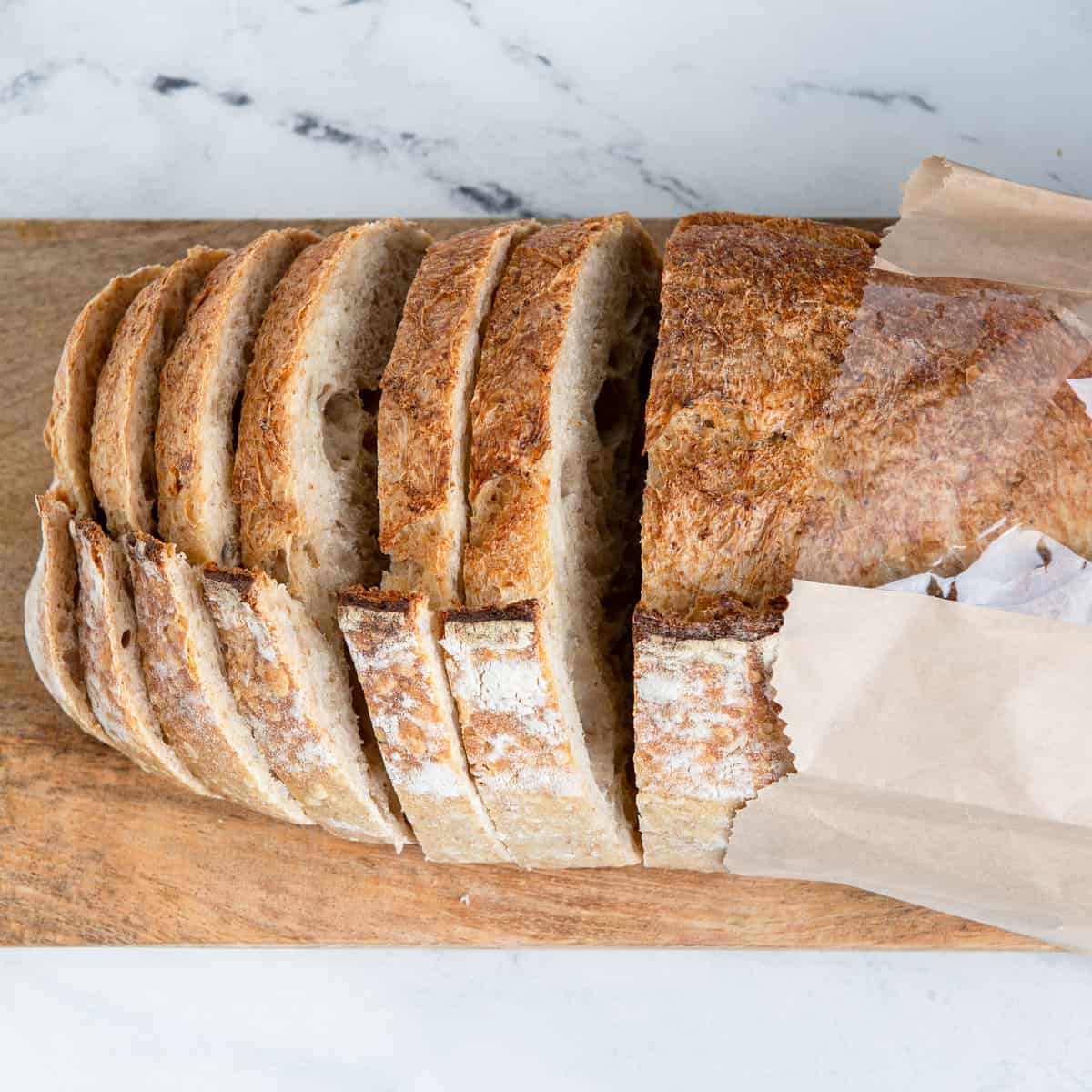 Sourdough bread sliced with bag on a bread board.