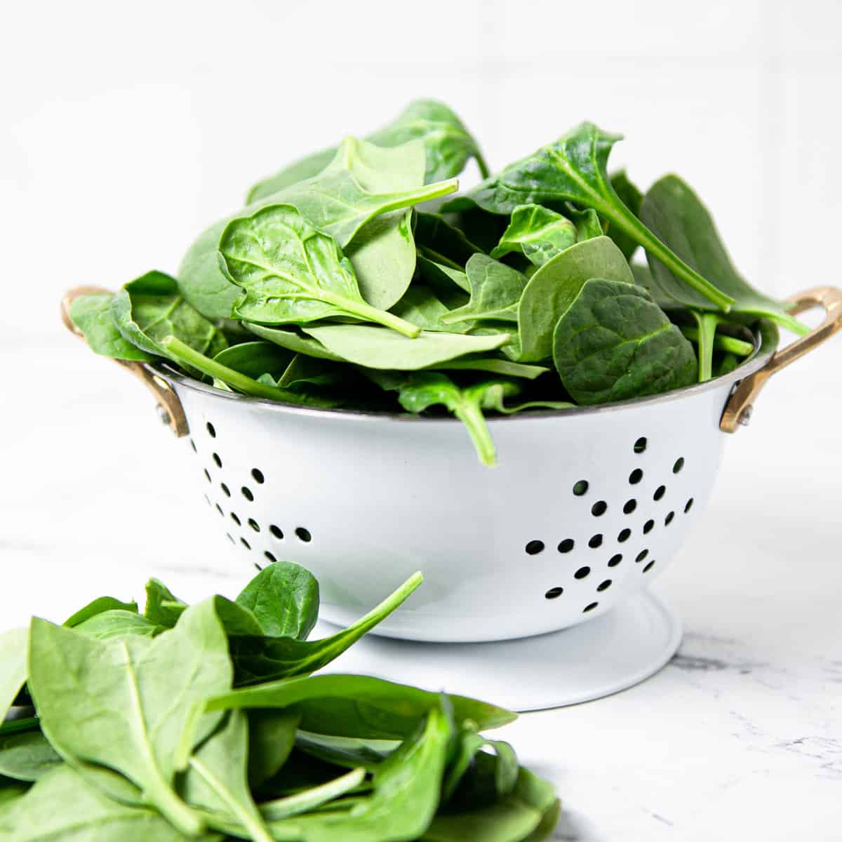 Spinach in colander on a counter.