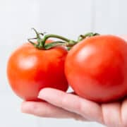 Two tomatoes in hand.