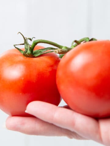 Two tomatoes in hand.