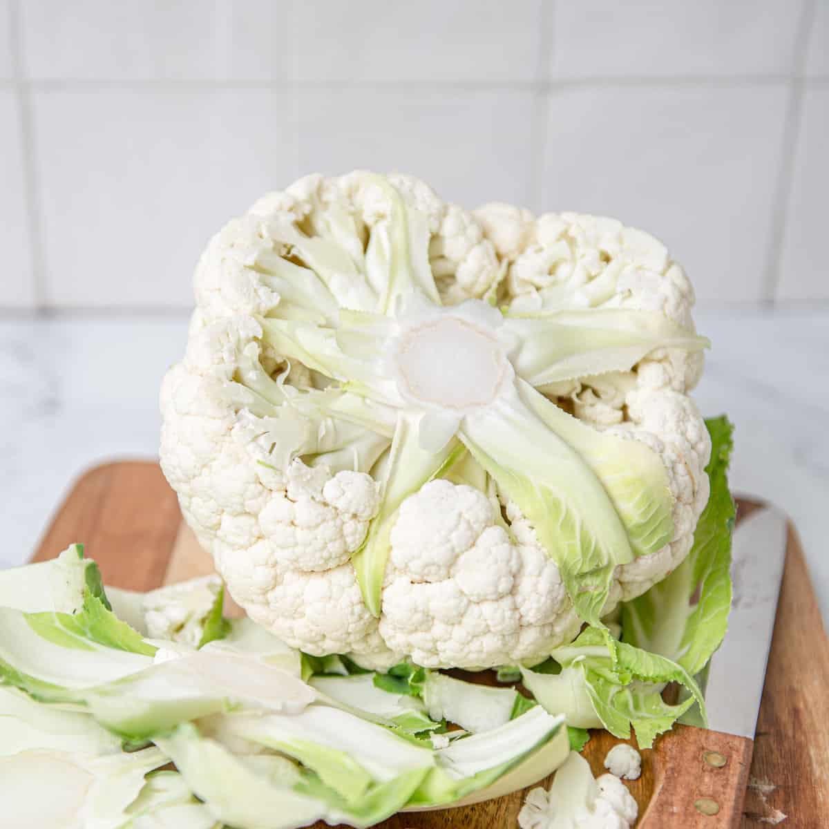 Trimmed cauliflower on a cutting board.