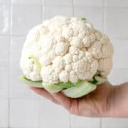 Whole head of cauliflower being held in one hand.