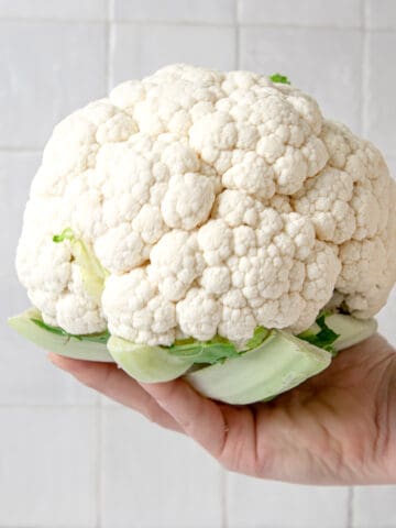 Whole head of cauliflower being held in one hand.